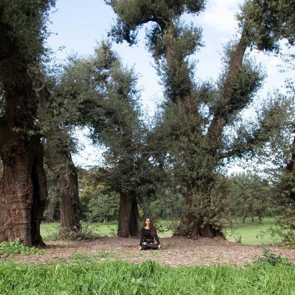 Woman meditating peacefully in a green, natural environment.